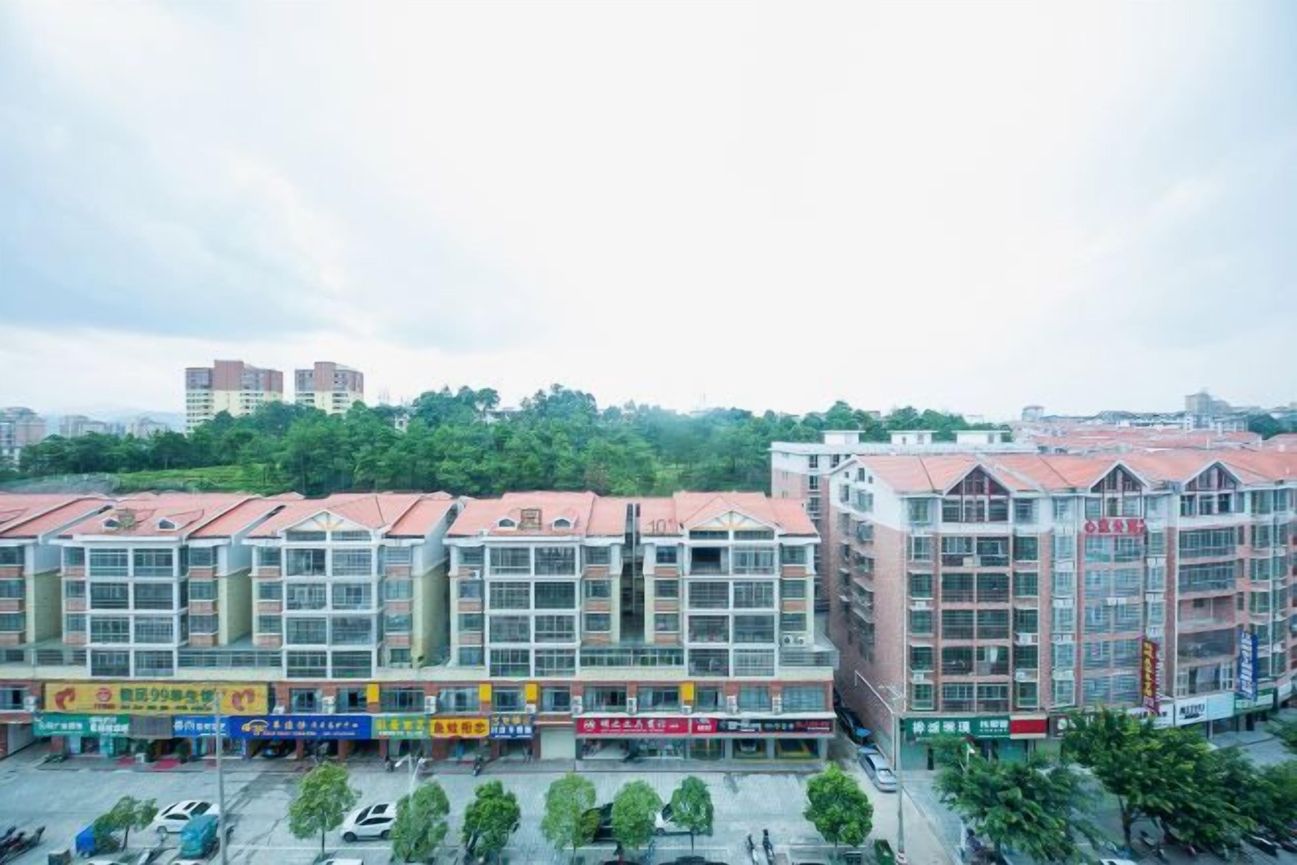 A multi-story building with a commercial ground floor, featuring various storefronts and a parking lot.