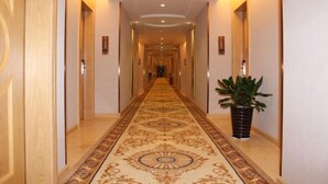 A long, narrow hallway with a patterned carpet and a potted plant on the right. - Vienna Hotel (Yudu Railway Station) (Yudu)
