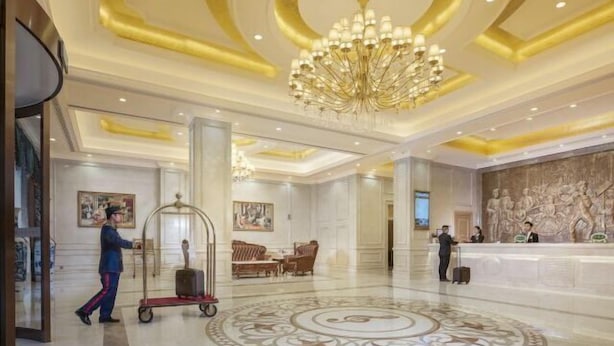 A spacious lobby with a grand chandelier, a reception desk, and a large decorative floor pattern. - Vienna Hotel (Yudu Railway Station) (Yudu)