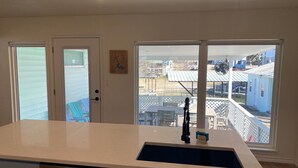 A kitchen with a large island, a sink, and a view of a neighborhood with houses and a playground. - Waterfront 5/3 roomy home, constant level Lake LBJ, jet ski ramp & covered porch (Kingsland)