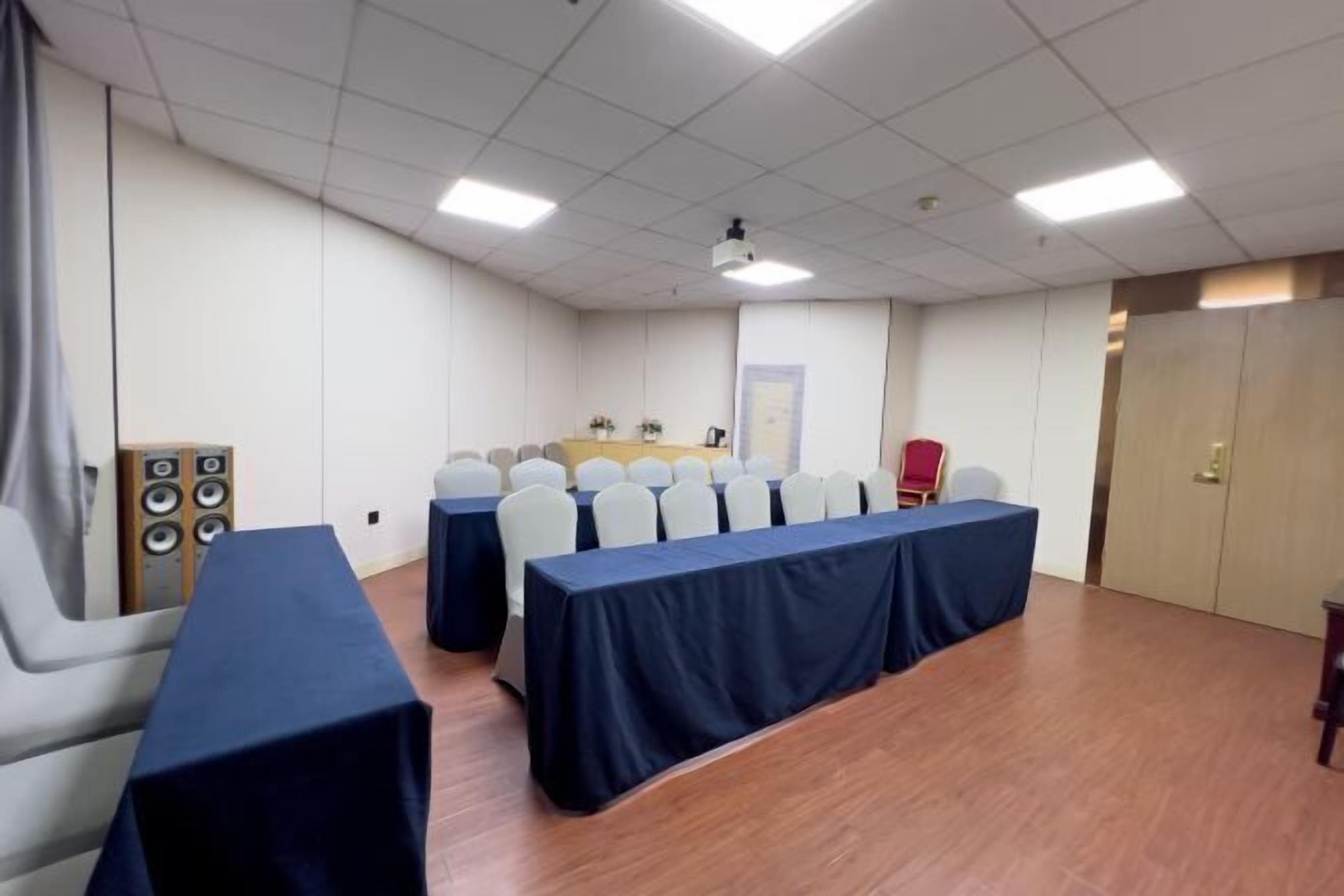 A conference room with a long table, chairs, a projector, and a speaker system.