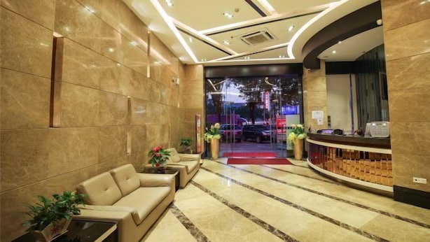 A hotel lobby with a reception desk, a seating area with sofas, and a glass entrance. - Jiangmen Park Lane Yiju Hotel (Wuyi University Baishi) (Jiangmen)