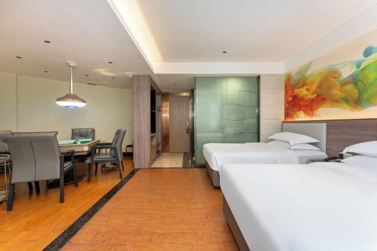 Habitación de hotel con zona de comedor, dos camas, un cuadro y un diseño moderno en el techo.