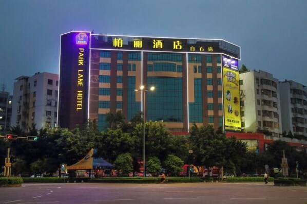 A multi-story hotel with illuminated signage, a prominent entrance, and a parking area in front.