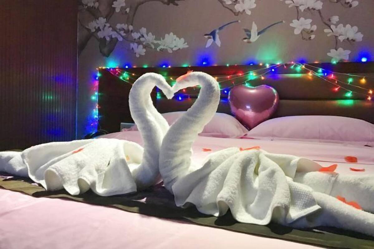Una cama con una toalla dispuesta en forma de corazón y una almohada de corazón rosa.