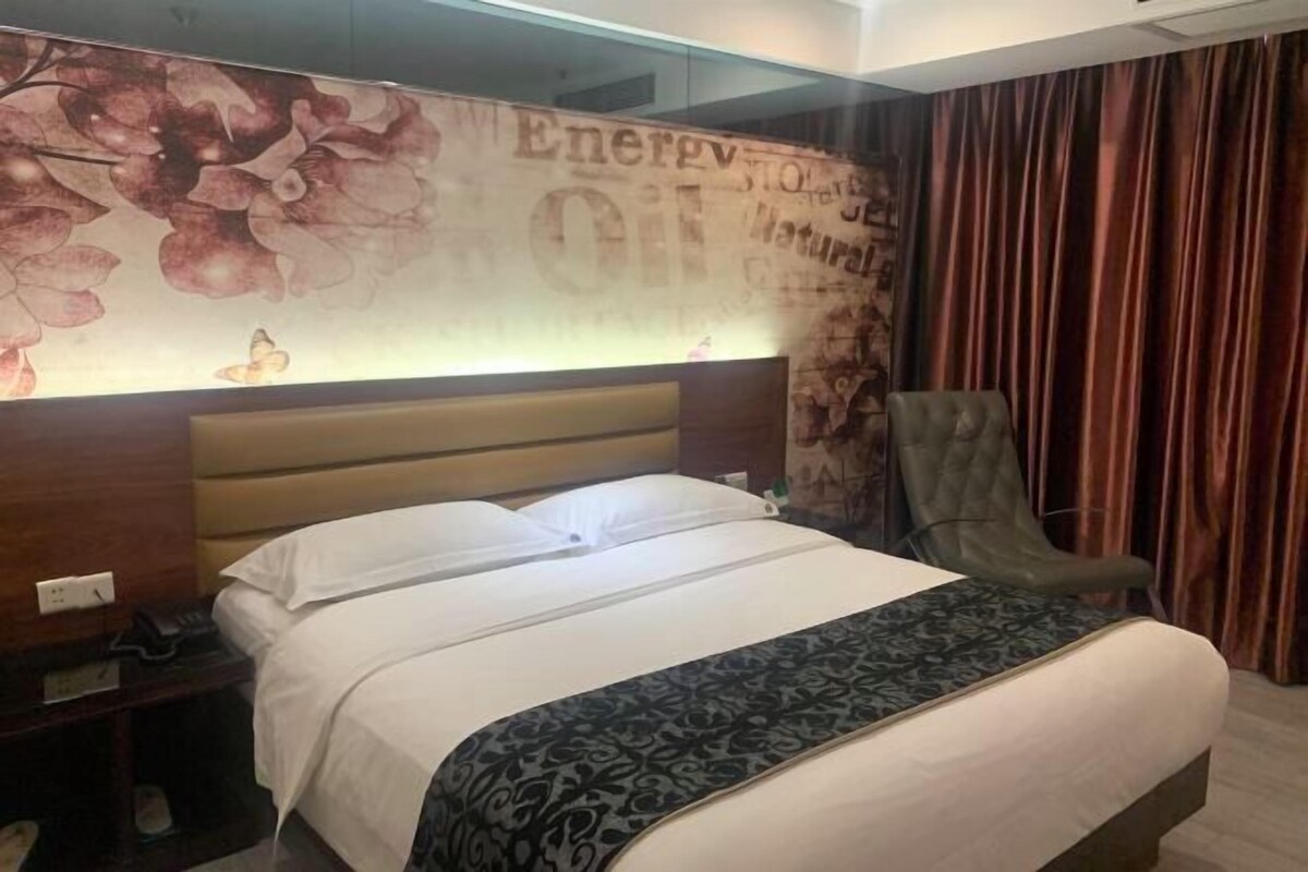 Une chambre d’hôtel comprenant un lit, une table de chevet, une chaise et un mur décoré de motifs floraux et d’inscriptions.