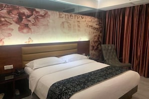 A hotel room with a bed, a nightstand, a chair, and a wall with floral and text decorations. - Jiangmen Park Lane Yiju Hotel (Wuyi University Baishi) (Jiangmen)