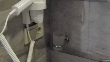 A bathroom with a white hairdryer, a small sink, and a mirror.