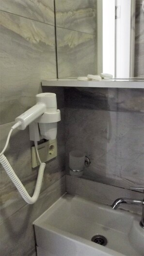 A bathroom with a white hairdryer, a small sink, and a mirror. - Miss City Hotel Taksim (Istanbul)