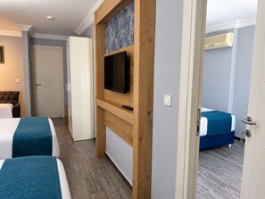 A hotel room with two beds, a television mounted on a wooden panel, a door, and an air conditioning unit. - Miss City Hotel Taksim (Istanbul)