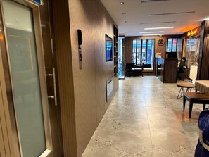 A hotel lobby with a wooden reception desk, seating area, and a view through the glass doors. - Miss City Hotel Taksim (Istanbul)