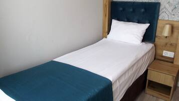 A single bed with a white mattress and a teal throw blanket.