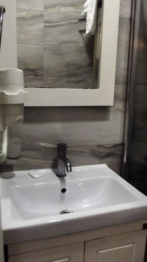 A bathroom with a white sink, a mirror above it, and a towel hanging on the wall. - Miss City Hotel Taksim (Istanbul)