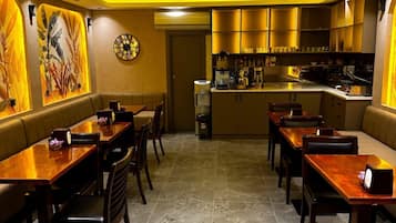 Un restaurante con cabinas y mesas, una zona de cocina y un reloj en la pared.