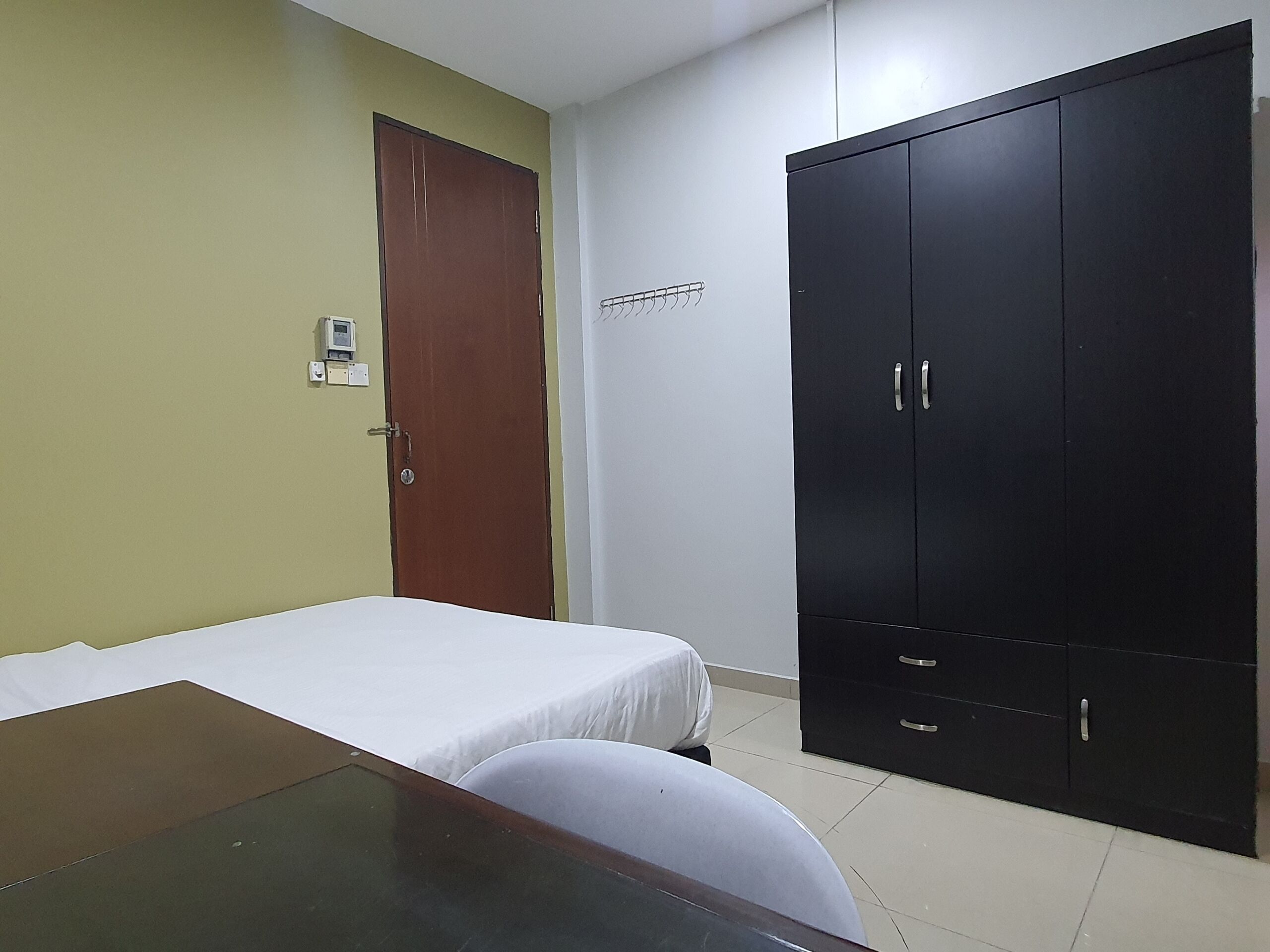 A room with a bed, a desk, a wardrobe, and a door.
