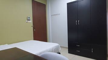 A room with a bed, a desk, a wardrobe, and a door.