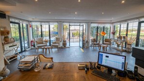 Een ruime kamer met een houten bureau, meerdere stoelen en een groot raam met uitzicht op de omgeving.
