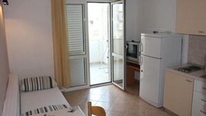 A compact kitchen with a refrigerator, microwave, and a small dining area with a table and chair.
