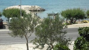 A coastal road with a rocky outcrop and a small boat near the water.