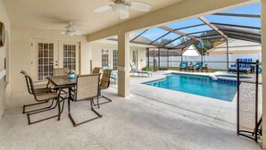 Un patio couvert avec une piscine, des ventilateurs de plafond et du mobilier d’extérieur.