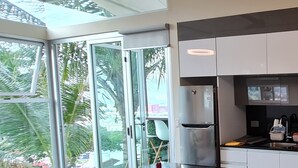 A modern kitchen with a large window, a refrigerator, and a dining area with a table and chairs. - Cozy Escazú Apartment with great view & location (Escazú)