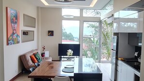 A modern kitchen with a central island, a dining area with a wooden table and chairs, and a sofa with cushions. - Cozy Escazú Apartment with great view & location (Escazú)