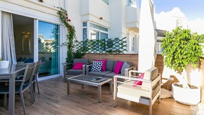 Ein Balkon mit Gartenmöbeln, einem Blumentopf und Blick auf die Stadt.