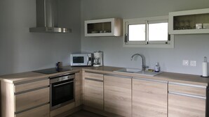Une cuisine moderne équipée d’une hotte en acier inoxydable, d’un four à micro-ondes, d’une machine à café et d’un évier.