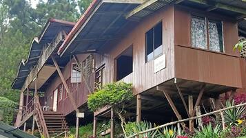 A wooden house with a balcony and a 'For Rent' sign.