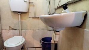 Pieni kylpyhuone, jossa on wc, pesuallas ja ämpäri.