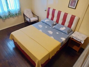 Een slaapkamer met een bed, een stoel en een nachtkastje.