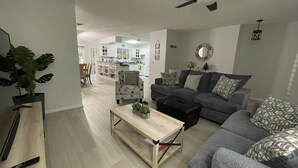 A modern living room with a grey sofa, a wooden coffee table, and a ceiling fan.
