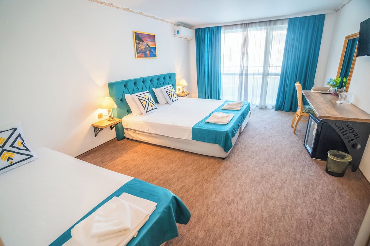 Een hotelkamer met twee bedden, een bureau, een stoel en een prullenbak.