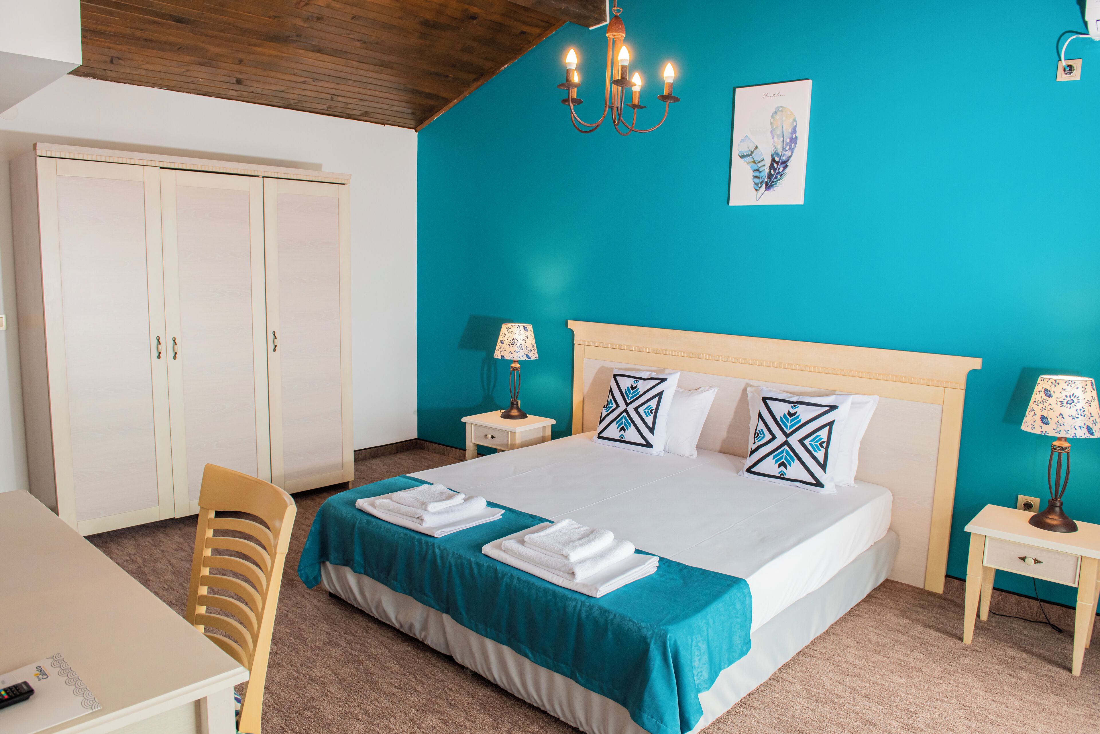 Una habitación de hotel con cama, escritorio, silla, armario y candelabro.