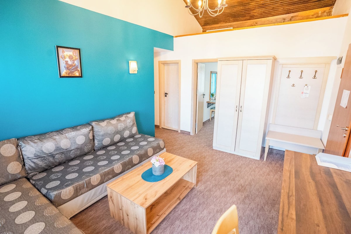 Een woonkamer met een bank, een bijzettafeltje en een schilderij aan de muur.