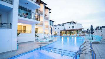 A hotel with a swimming pool, lounge chairs, and a restaurant.