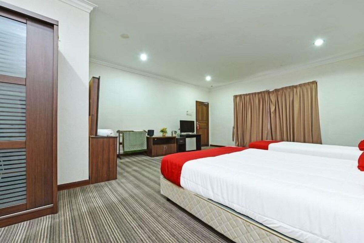 A hotel room with a bed, a desk, a television, and a window with curtains.