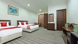 A hotel room with two beds, a desk, a chair, a wardrobe, and a painting on the wall.