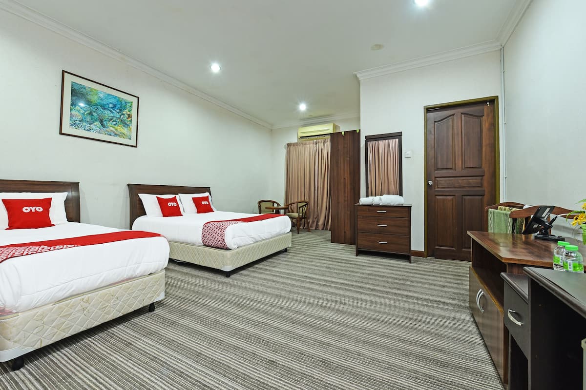 A hotel room with two beds, a desk, a chair, a wardrobe, and a painting on the wall.