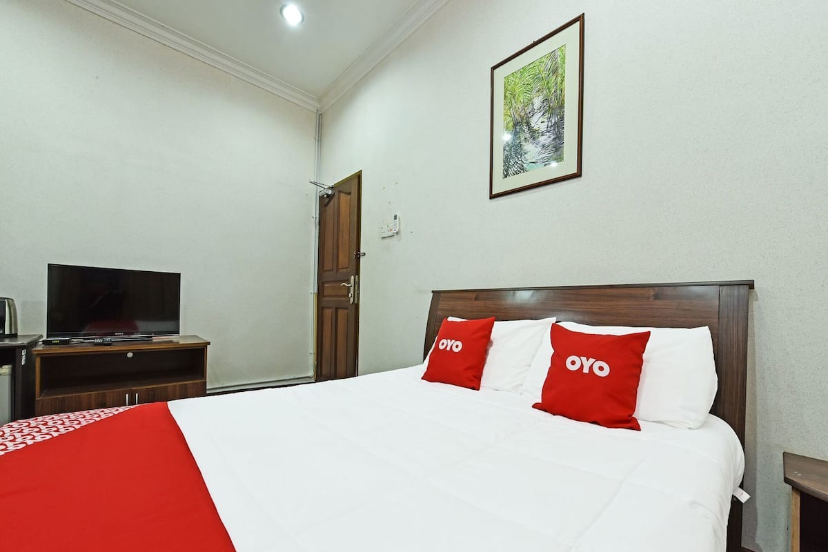 A hotel room with a bed, a television, and a door.