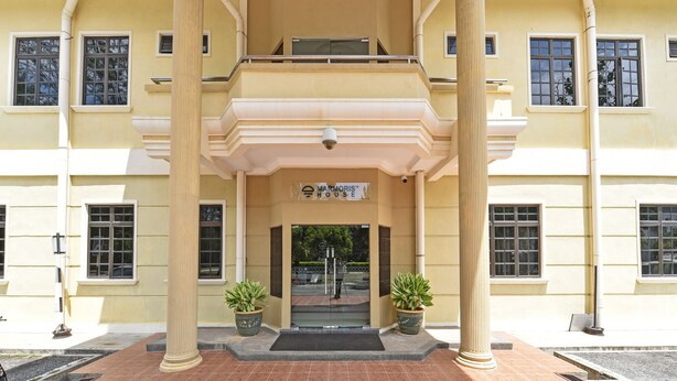A building with a symmetrical facade, large windows, and a central entrance with a sign.