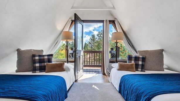 Une chambre avec deux lits, une grande fenêtre et une vue sur l’extérieur.
