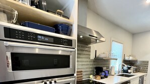 Une cuisine moderne dotée de deux fours en acier inoxydable, d’une plaque de cuisson intégrée et d’un pare-feu orné d’un motif en briques.