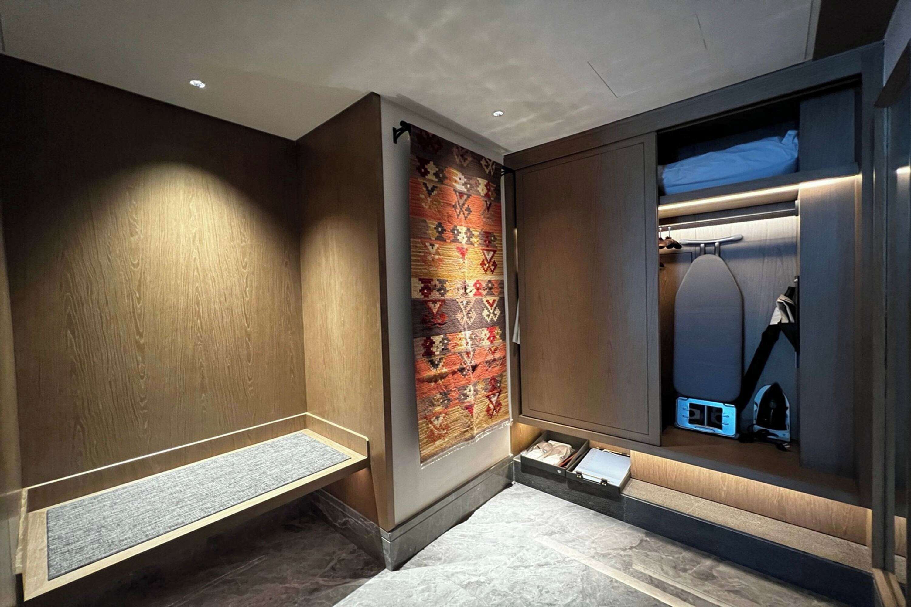 Un baño moderno con tocador de madera, alfombra estampada y espejo con iluminación integrada.