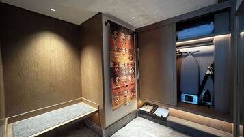 Un baño moderno con tocador de madera, alfombra estampada y espejo con iluminación integrada.