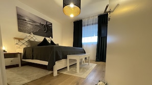 A bedroom with a bed, bedside table, lamp, and a wall-mounted picture. - Shopping, vacation or business - you've finally come to the right place (Metzingen)