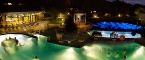 Zona de piscina con varias piscinas y un área de descanso techada.