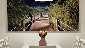 A dining area with a white table and chairs, a vase with flowers, and a large framed picture above the table. - Shopping, vacation or business - you've finally come to the right place (Metzingen)