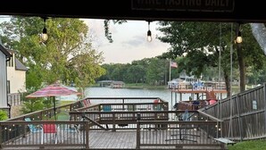 A wooden deck with a view of a lake, a dock, and a boat. - Beautiful 4/3 waterfront home with 2 master suites (Tool)