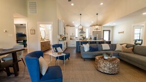 A spacious living area with a dining table, blue armchairs, a sofa, and a coffee table. - Beautiful 4/3 waterfront home with 2 master suites (Tool)